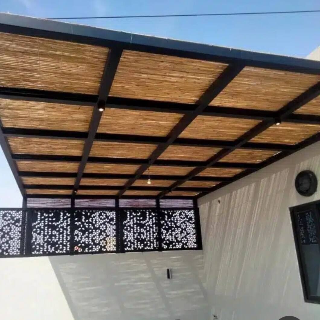 مظلة جدارية بهيكل حديدي أسود وتغطية من ألواح القصب مثبتة على جدار المبنى مع لوح حديد مزخرف